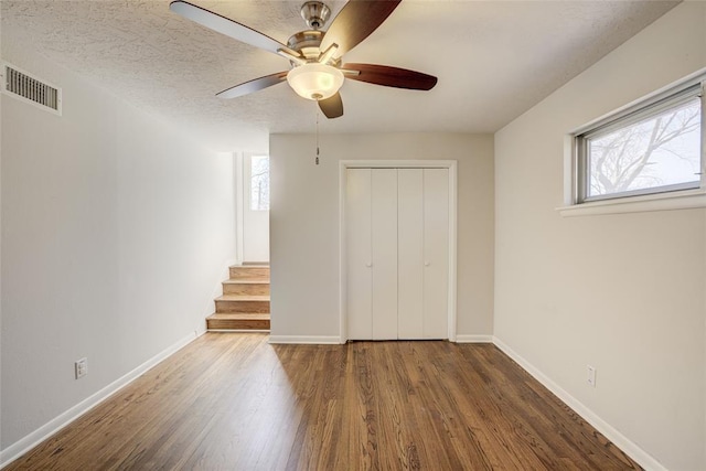 unfurnished bedroom featuring baseboards, visible vents, multiple windows, and wood finished floors