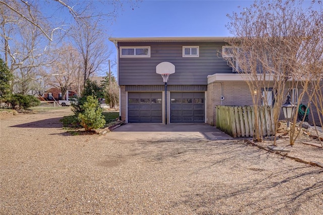 exterior space featuring an attached garage, dirt driveway, and brick siding
