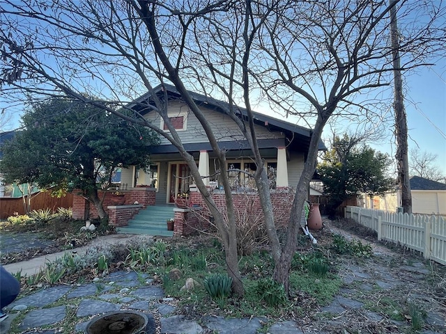 view of front of property with brick siding and fence