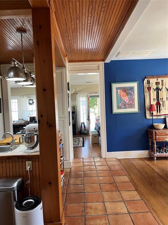 hall featuring visible vents, a sink, wooden ceiling, tile patterned flooring, and baseboards