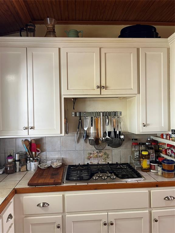 kitchen featuring backsplash, white cabinets, stainless steel gas cooktop, and tile countertops