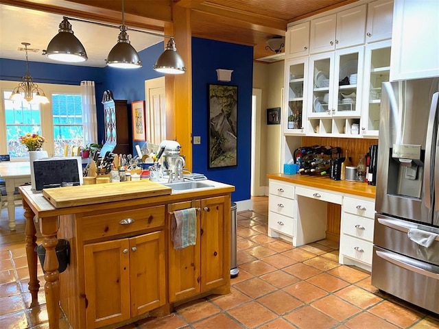 kitchen with wood ceiling, stainless steel refrigerator with ice dispenser, white cabinetry, wood counters, and a sink