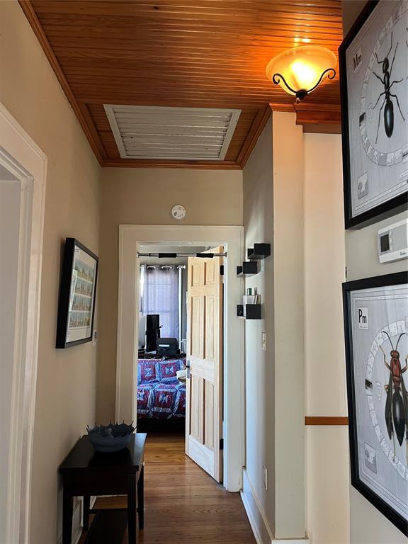 hallway featuring visible vents, dark wood-type flooring, wooden ceiling, and ornamental molding