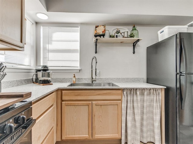 kitchen with light brown cabinetry, a sink, open shelves, freestanding refrigerator, and light countertops