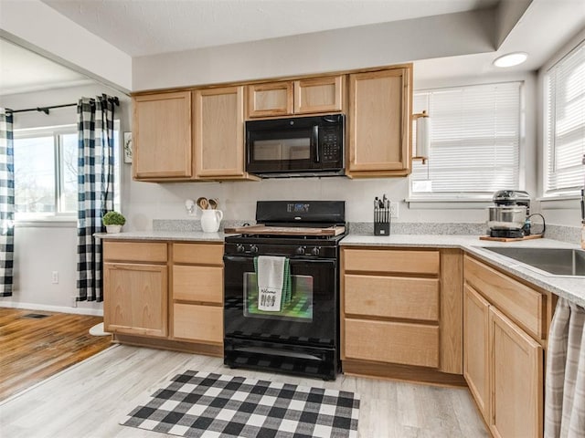 kitchen with black appliances, plenty of natural light, light brown cabinets, and a sink