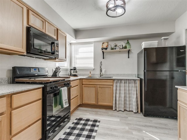 kitchen with light brown cabinets, light wood finished floors, a sink, black appliances, and a textured ceiling