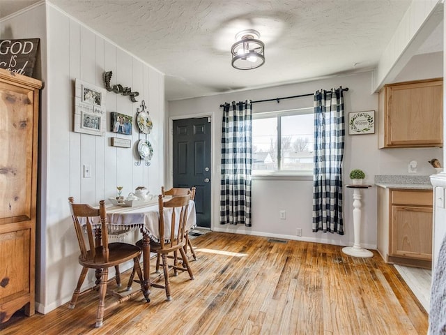 dining room featuring visible vents, baseboards, a textured ceiling, and light wood-style flooring