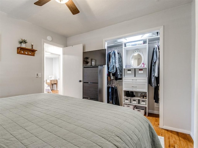 bedroom featuring a ceiling fan, baseboards, a spacious closet, light wood-style floors, and a closet