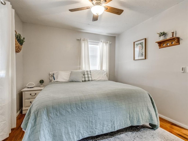 bedroom with baseboards, wood finished floors, and a ceiling fan