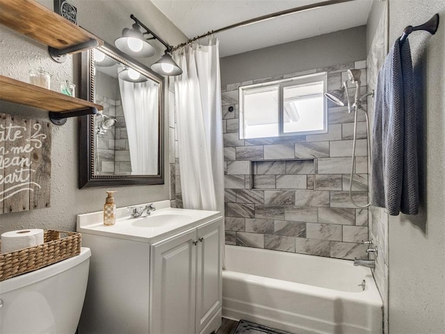 bathroom with vanity, toilet, a textured wall, and shower / bath combo