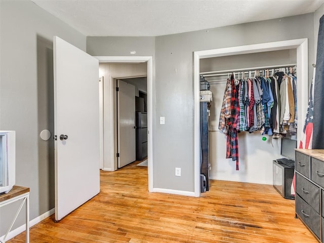 bedroom featuring light wood-style floors, a closet, and baseboards