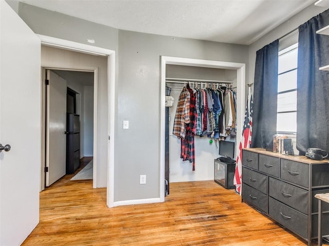 bedroom with a closet, light wood-style flooring, and baseboards