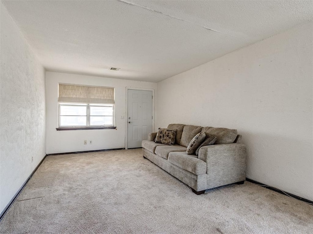 carpeted living area with visible vents, a textured ceiling, and a textured wall