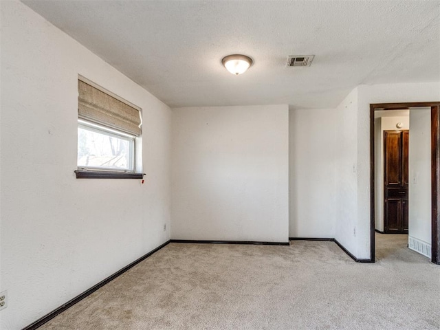 carpeted spare room featuring visible vents, baseboards, and a textured ceiling