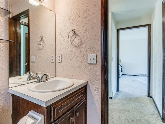 bathroom featuring vanity, a textured wall, and visible vents