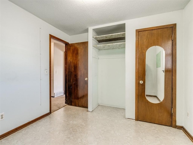 unfurnished bedroom with a closet, visible vents, a textured ceiling, and baseboards