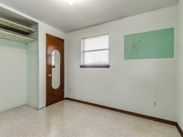 interior space with light floors, baseboards, and a textured ceiling