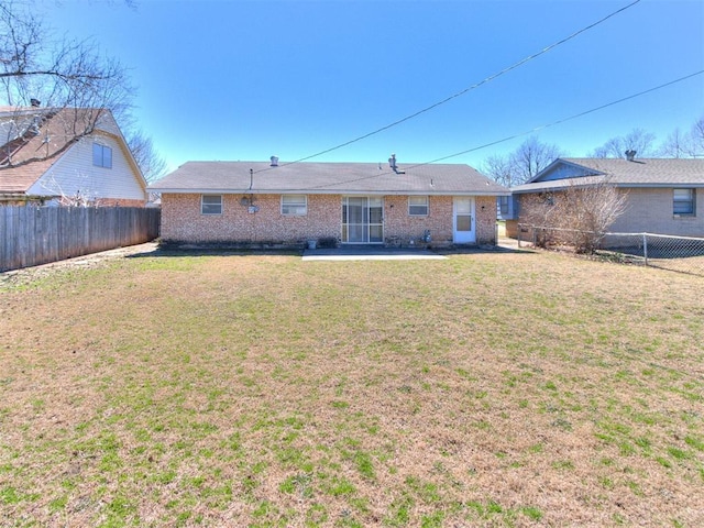 back of house featuring a lawn, a fenced backyard, brick siding, and a patio area