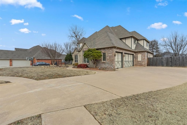 view of home's exterior with fence, driveway, roof with shingles, an attached garage, and brick siding