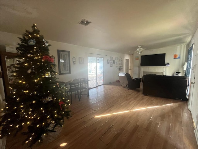 living area with visible vents, a fireplace, ceiling fan, and wood finished floors