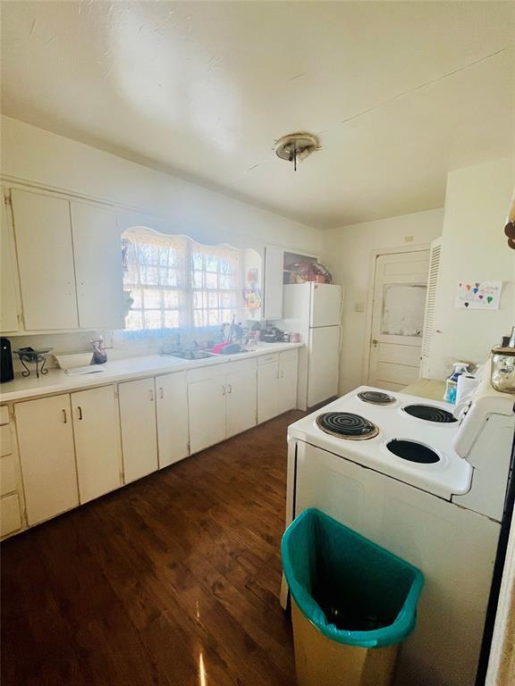 kitchen with white cabinetry, dark wood-style floors, light countertops, and freestanding refrigerator