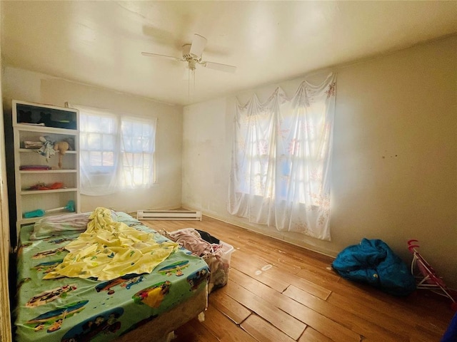 bedroom featuring hardwood / wood-style flooring, a ceiling fan, and baseboard heating