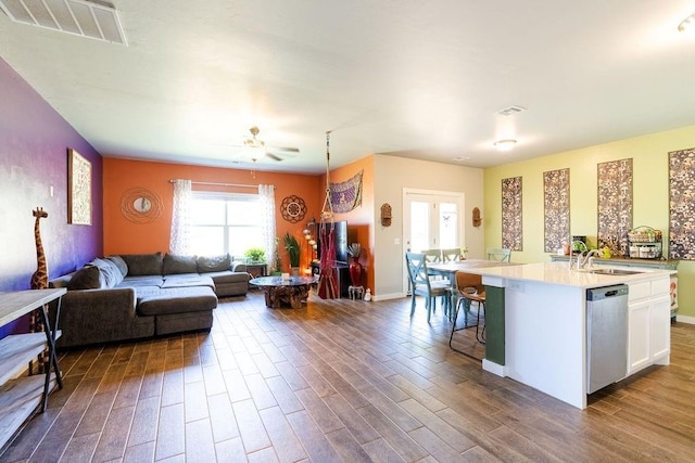 living area featuring visible vents, baseboards, ceiling fan, and dark wood-style flooring