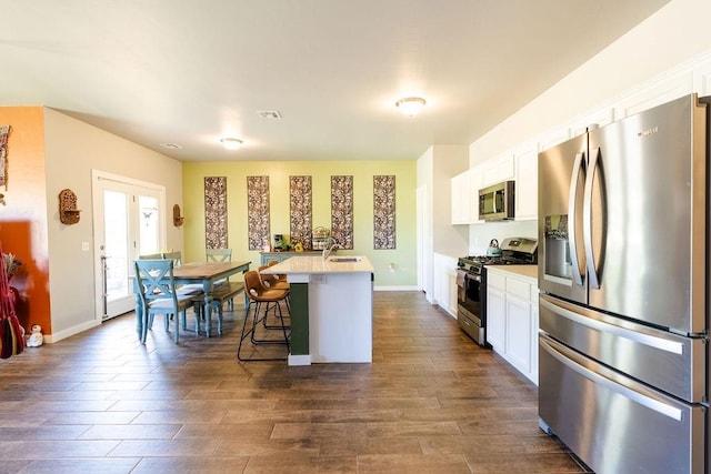 kitchen featuring a breakfast bar area, light countertops, appliances with stainless steel finishes, white cabinets, and a kitchen island with sink