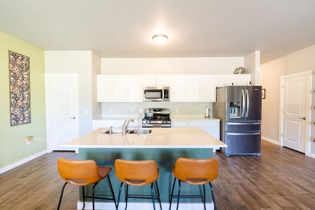 kitchen with a breakfast bar, a sink, stainless steel appliances, dark wood-type flooring, and white cabinets