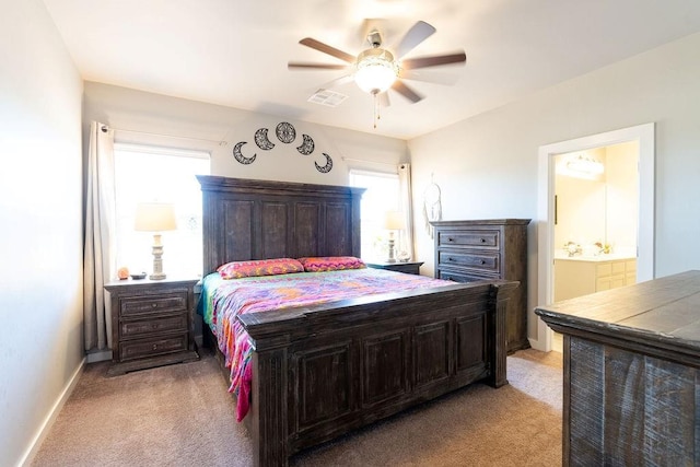 bedroom with visible vents, light colored carpet, baseboards, and connected bathroom