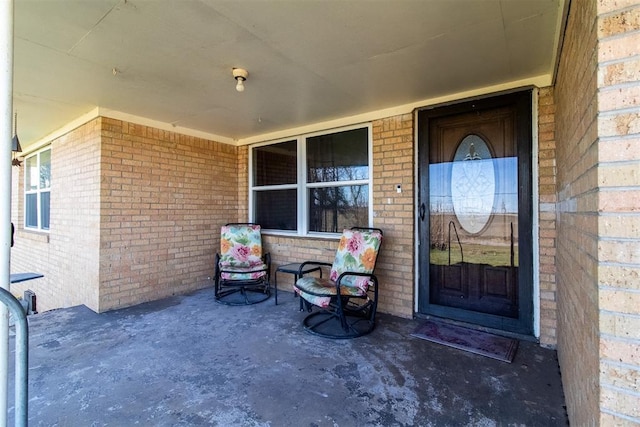 entrance to property with brick siding and a porch