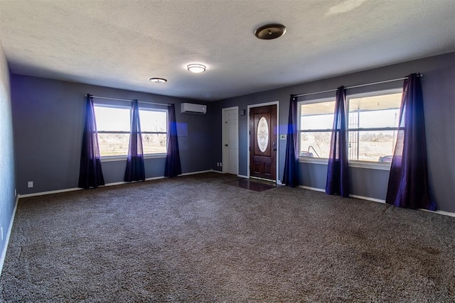 foyer with a healthy amount of sunlight, a textured ceiling, a wall mounted AC, and carpet floors