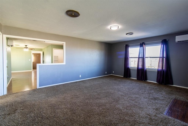 unfurnished room with carpet flooring, a textured ceiling, a wall mounted air conditioner, and baseboards