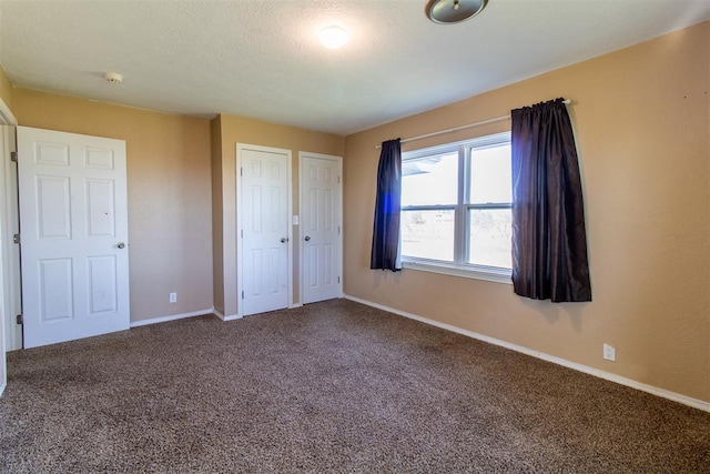 unfurnished bedroom featuring carpet flooring, a textured ceiling, and baseboards