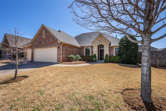 view of front of property featuring a front yard, fence, concrete driveway, a garage, and brick siding