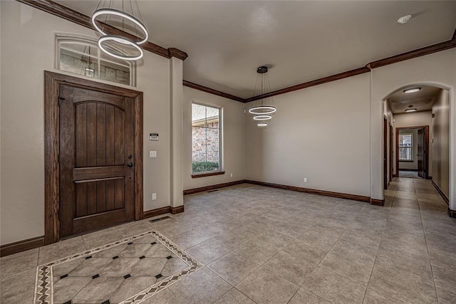 foyer with arched walkways, visible vents, baseboards, and ornamental molding