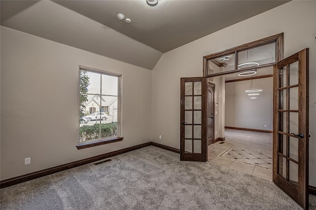 spare room featuring visible vents, french doors, baseboards, light colored carpet, and vaulted ceiling