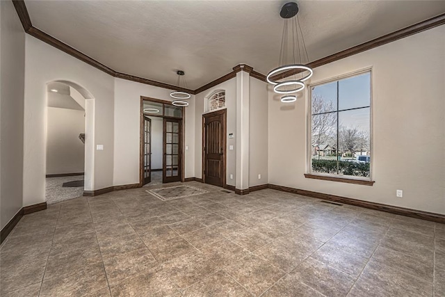 empty room with baseboards, arched walkways, and ornamental molding