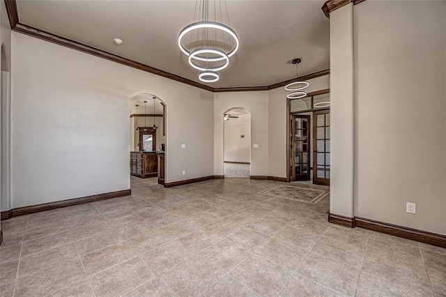 spare room featuring baseboards, arched walkways, and ornamental molding