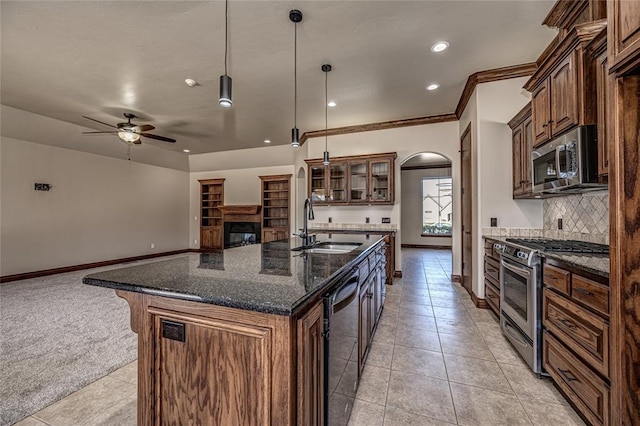 kitchen featuring a ceiling fan, arched walkways, a sink, appliances with stainless steel finishes, and backsplash