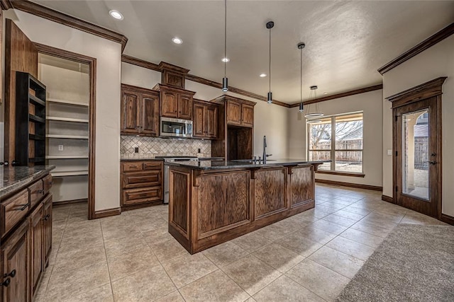 kitchen featuring tasteful backsplash, light tile patterned floors, a center island with sink, and stainless steel appliances