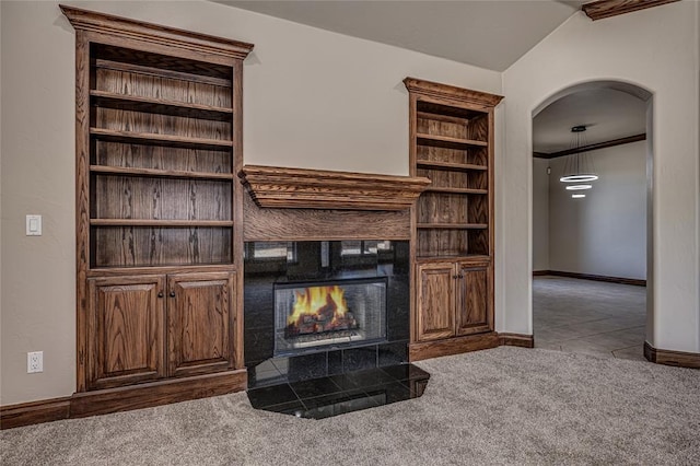 unfurnished living room with lofted ceiling, arched walkways, carpet, a fireplace, and baseboards