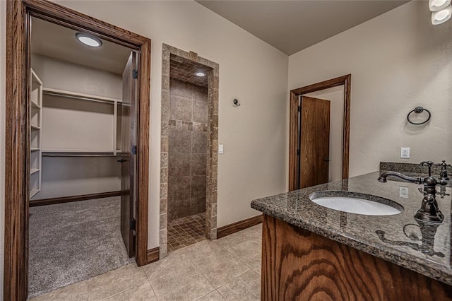 full bath with vanity, tile patterned floors, baseboards, and a tile shower