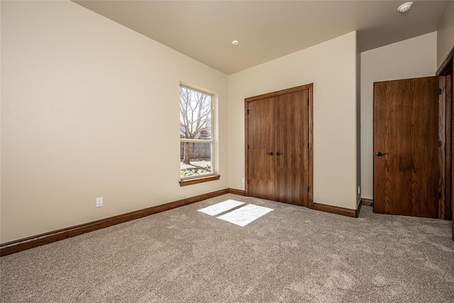 unfurnished bedroom featuring carpet, baseboards, and a closet