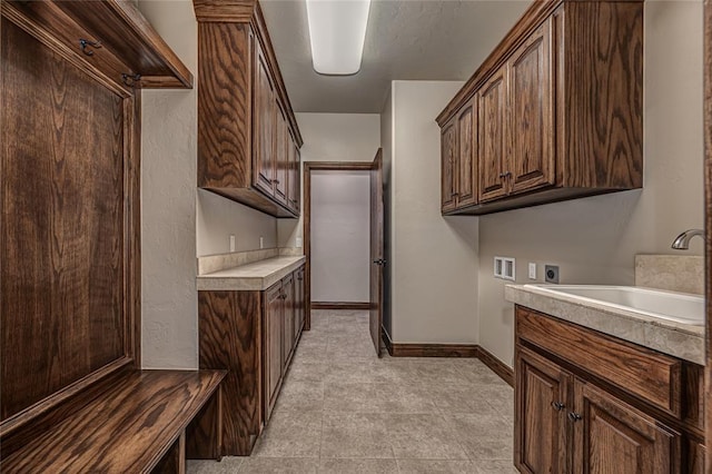 laundry room featuring baseboards, cabinet space, a sink, washer hookup, and electric dryer hookup