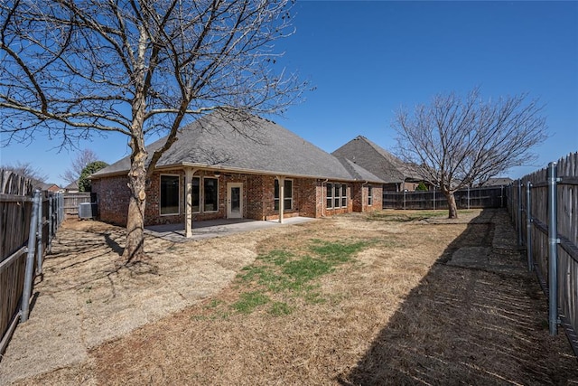 back of house with brick siding, central AC, roof with shingles, a fenced backyard, and a patio area