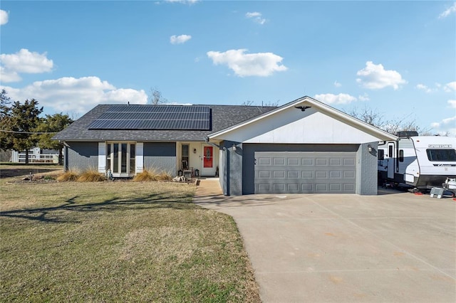 view of front of home with driveway, a front lawn, roof mounted solar panels, roof with shingles, and an attached garage