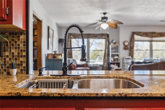 kitchen with decorative backsplash, dark brown cabinets, a ceiling fan, and a sink