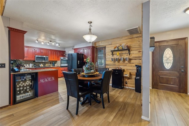 dining area featuring light wood-style floors, visible vents, and a textured ceiling