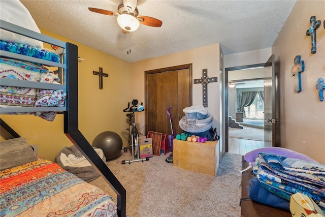 carpeted bedroom featuring a closet, a textured ceiling, and ceiling fan